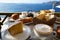 Beautiful island breakfast with Aegean sea view including cappuccino cup, cake, baguette, croissant, boiled egg, hot tea