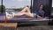 Beautiful joyful girl with dark long hair and long bare legs resting in the sun lying on a lounger. Woman in sunglasses