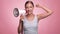 A beautiful joyful girl in a striped T-shirt shouts into the loudspeaker on isolated pink background