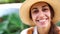 Beautiful joyful tourist woman in straw hat and white shirt looking and smiling at camera