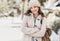 Beautiful joyful woman autumn portrait. Smiling student girl wearing warm clothes and hat in a city in winter