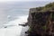 Beautiful jungle beach cliff with blue ocean at Bali Indonesia with yellow sand and green forest in the back.