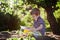 Beautiful kid boy, reading a book in garden, sitting next to a t