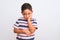 Beautiful kid boy wearing casual striped t-shirt standing over isolated white background thinking looking tired and bored with