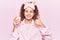 Beautiful kid girl with curly hair wearing sleep mask and pajama holding milk smiling happy and positive, thumb up doing excellent
