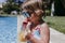 beautiful kid girl at the pool drinking healthy orange juice and having fun outdoors. Summertime and lifestyle concept