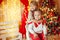 Beautiful kids brother and sister on kami background with Christmas lights and Christmas tree decorated with garland