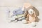 A beautiful knitted toy with a stack of children`s clothes and a baby bottle on a white chest of drawers, motherhood, expecting
