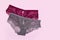 Beautiful lace lingerie on a pink isolated background. Gray and burgundy classic briefs