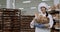 Beautiful lady baker in a white uniform holding a basket with fresh bread and smiling cute in front of the camera