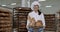 Beautiful lady baker in a white uniform holding a basket with fresh bread and smiling cute in front of the camera