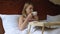 Beautiful lady enjoying morning coffee in bed, hotel room service, weekend