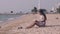 Beautiful lady with long dark hair reads book on sand beach