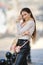 Beautiful lady with long healthy hair and scarf on her neck standing on the street in windy day in profile