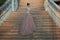 Beautiful lady in luxurious ballroom dress walking up the stairs of her palace