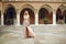 Beautiful lady in luxurious pink ballroom dress. Blond walking along the old castle. The blonde looks at the camera and travels