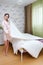 Beautiful lady in purl coral white robe posing holding blanket on the bed in white interior bedroom