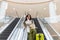 Beautiful lady tourist going down with baggage on escalator at terminal of international airport
