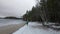 A beautiful lady traveler enjoying the view of a peaceful winter wonderland while walking by the frozen lake in the middle of a fo