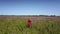 Beautiful lady wearing red summer dress walks on wide field