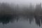 The beautiful Lago di Carezza with reflections in fog