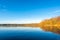 Beautiful lake landscape, reflections of golden birch forest and blue sky
