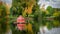 Beautiful lake with small wooden houses for ducks and autumn willow trees with green, yellow leaves in city park. Moscow