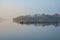 Beautiful landcape image of Spring sunrise over reservoir lake with dawn glow spreading aross the water with low mist adding
