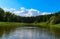 Beautiful landscape with blue sky and white clouds reflected in the clear river water. Summer idyllic .