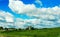 beautiful landscape with greenery, clouds, blue sky and village buildings.