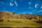 Beautiful landscape. Hills and meadows in sunlight, blue sky with light white clouds. Early autumn in the mountains