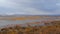 Beautiful landscape of lake with peaceful water and colorful plants in autumn, with snow mountain and cloudy sky background, Gahai