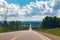 Beautiful landscape midday view of Canadian Ontario empty countryside road during sunny day with white clouds in blue sky.