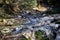 Beautiful landscape of mountain river in forest. Bright panorama of violent river between stones in spring