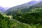 Beautiful landscape with mountains, forest and pines, river, twisting road and blue sky.