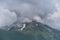 Beautiful landscape of National Park of Russia. Dark thundercloud envelops snowy mountain peak. Forest and mountains in fog in