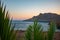 Beautiful landscape with palm leaves, sea and mountains on sunset. Tripiti beach