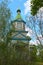 Beautiful landscape photo of ancient wooden church against blue sky in sunny day. The church is hiding in the trees.