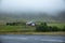 Beautiful landscape of a quiet house in a green field on a foggy day.