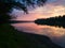 Beautiful landscape with river, forested riparian zone and hazy mountains in distance during sunset with colorful clouds in pink