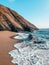 Beautiful landscape of rocky cliffs on the seashore, blue waves crashing on sandy beach
