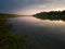 The beautiful landscape of the Sava River during a gloomy evening with a sunny pink glow that stretches under the clouds, and the