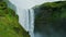 Beautiful landscape of the Skogafoss waterfall surrounded by green-covered cliffs