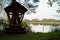 Beautiful landscape with small wooden gazebo and water of calm lake in a summer day. Concept of a walk, rest and travel to nature