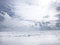 Beautiful landscape with snow-covered country field, the sun and clouds.