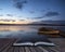 Beautiful landscape sunrise over still lake with boats on jetty