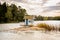 Beautiful landscape view of a small bath hut cottage on a rock in a lake surrounded by trees and reed.