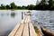 Beautiful landscape with water of calm lake and wooden walkway in a summer day. Concept of a walk, rest and travel on nature or in