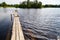 Beautiful landscape with water of calm lake and wooden walkway in a summer day. Concept of a walk, rest and travel on nature or in