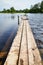 Beautiful landscape with water of calm lake and wooden walkway in a summer day. Concept of a walk, rest and travel on nature or in